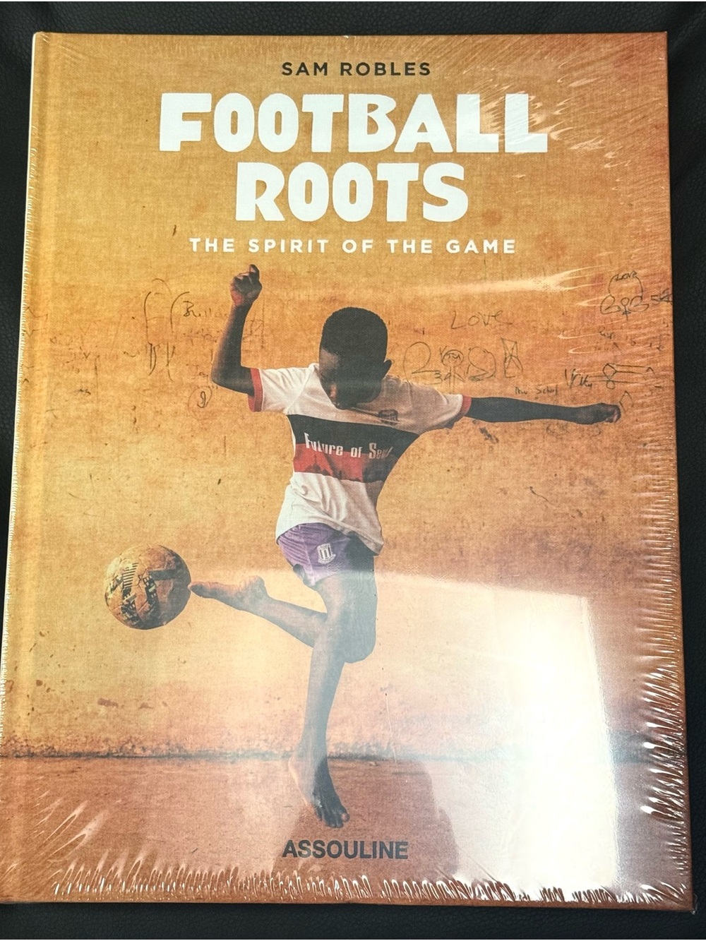 Assouline Football Roots Coffee Table Book — warm orange and white cover